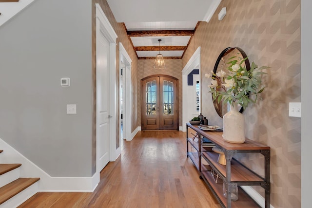 entryway featuring french doors, beamed ceiling, light wood-style flooring, and baseboards