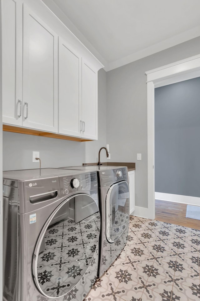 laundry room with ornamental molding, baseboards, cabinet space, and washing machine and clothes dryer