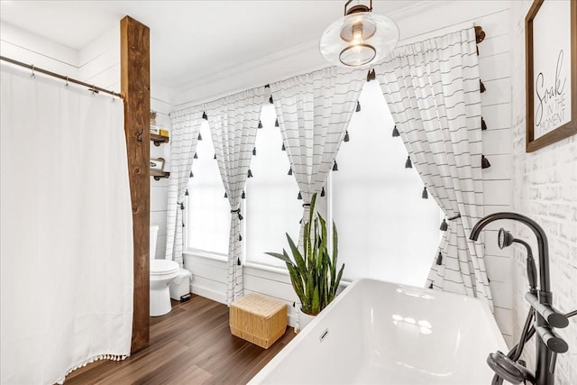 bathroom with toilet, ornamental molding, and wood finished floors