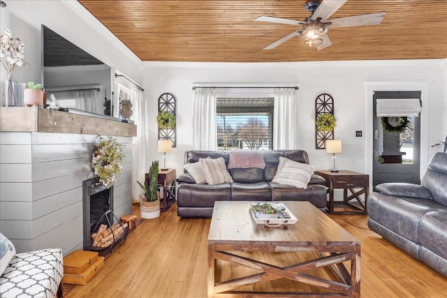 living room featuring ornamental molding, a fireplace, wooden ceiling, and wood finished floors