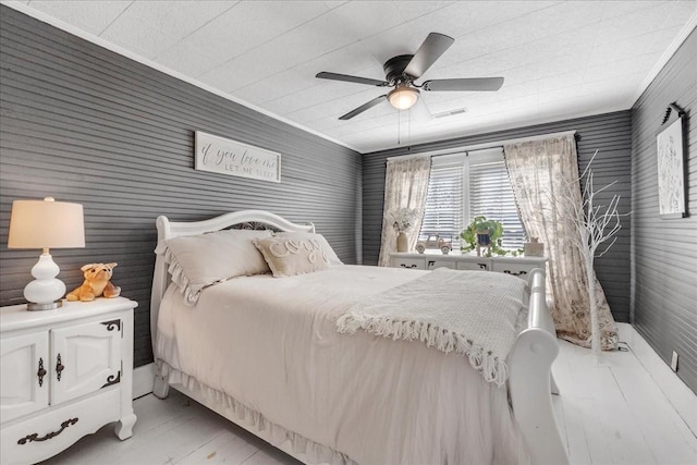 bedroom with visible vents, light wood-type flooring, a ceiling fan, and crown molding