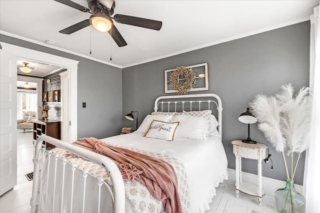 bedroom featuring ceiling fan, baseboards, crown molding, and wood finished floors