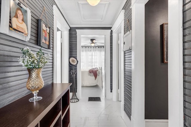 hallway with attic access, visible vents, and crown molding