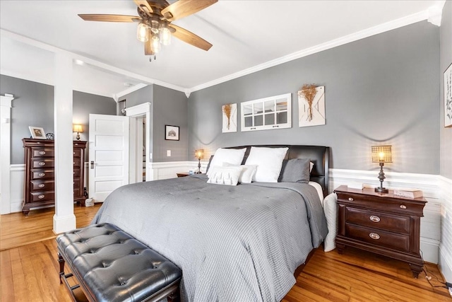 bedroom featuring a wainscoted wall, a ceiling fan, ornamental molding, and wood finished floors