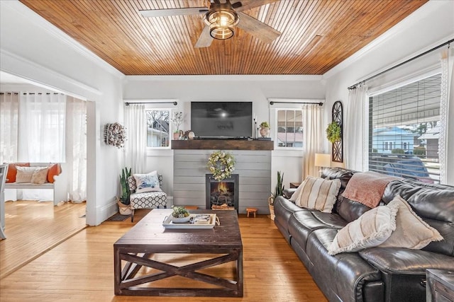 living area featuring light wood finished floors, ornamental molding, wood ceiling, and a ceiling fan