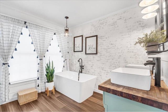 bathroom with a soaking tub, brick wall, ornamental molding, wood finished floors, and vanity