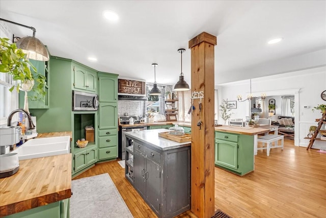 kitchen with butcher block countertops, appliances with stainless steel finishes, green cabinets, and a sink