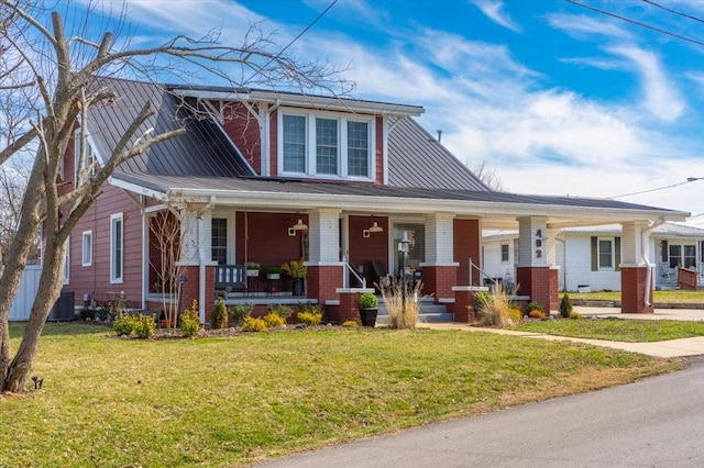 view of front of property featuring a porch, a front lawn, central AC unit, and brick siding