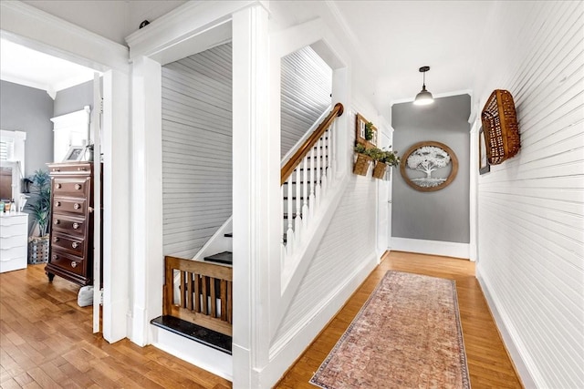 stairs with baseboards, wood finished floors, and ornamental molding