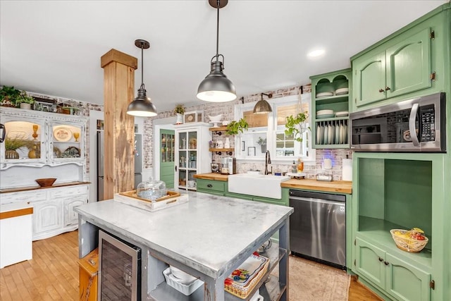 kitchen featuring open shelves, stainless steel appliances, green cabinets, a sink, and beverage cooler