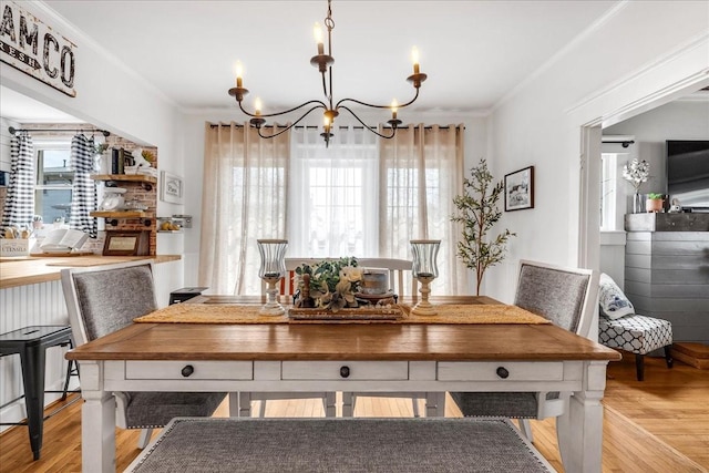 dining area featuring light wood-type flooring, an inviting chandelier, and crown molding