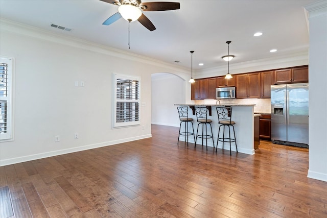 kitchen with appliances with stainless steel finishes, arched walkways, dark wood finished floors, and a breakfast bar