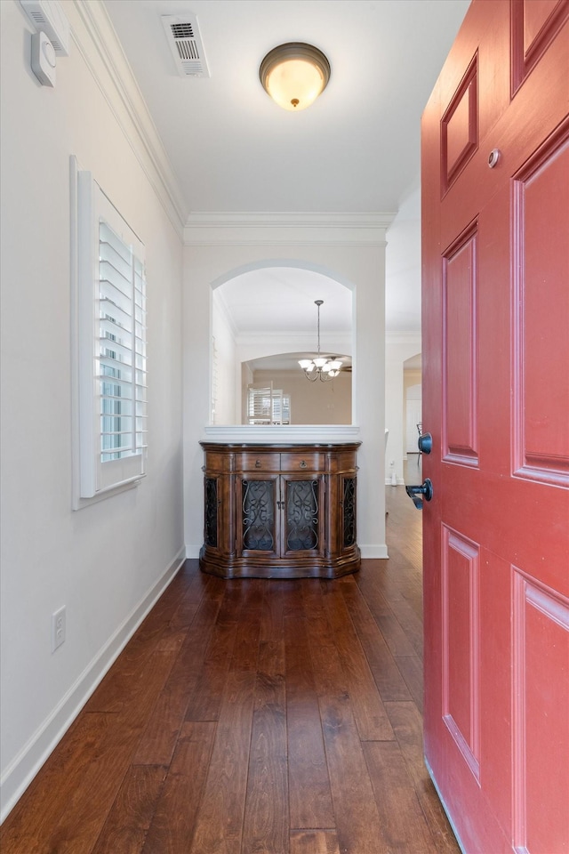 foyer entrance with baseboards, visible vents, dark wood finished floors, ornamental molding, and a notable chandelier