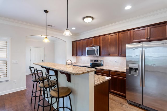 kitchen with arched walkways, dark wood finished floors, stainless steel appliances, tasteful backsplash, and visible vents