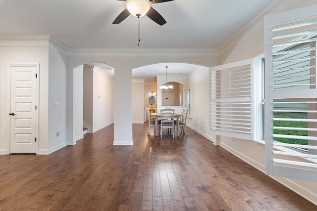 interior space with arched walkways, ceiling fan with notable chandelier, baseboards, dark wood finished floors, and crown molding