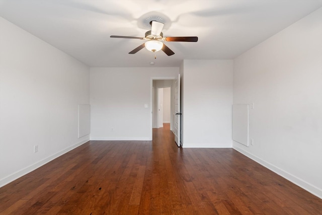 spare room featuring dark wood-type flooring, ceiling fan, and baseboards