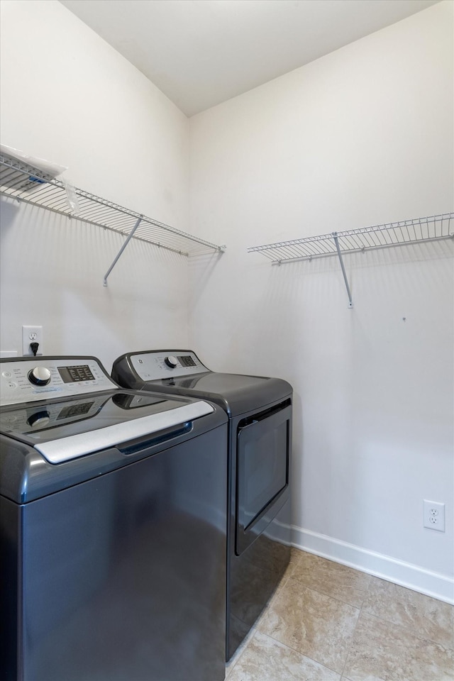 laundry area with laundry area, washing machine and dryer, and baseboards