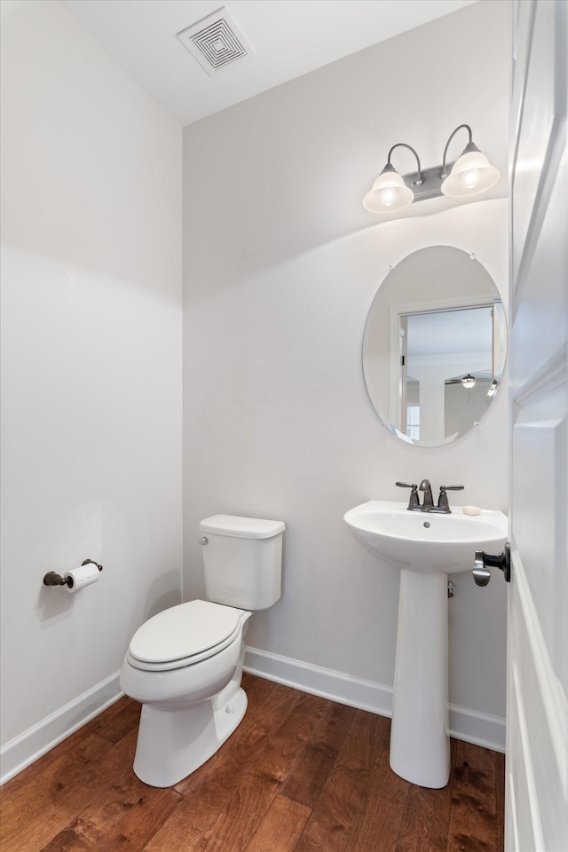 bathroom with visible vents, toilet, baseboards, and wood finished floors