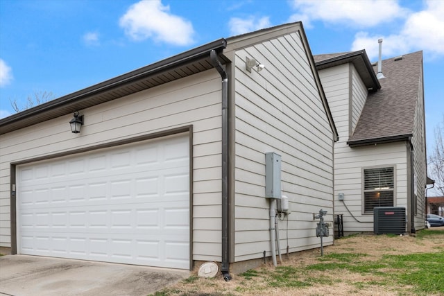 view of side of home with driveway, central AC, and roof with shingles