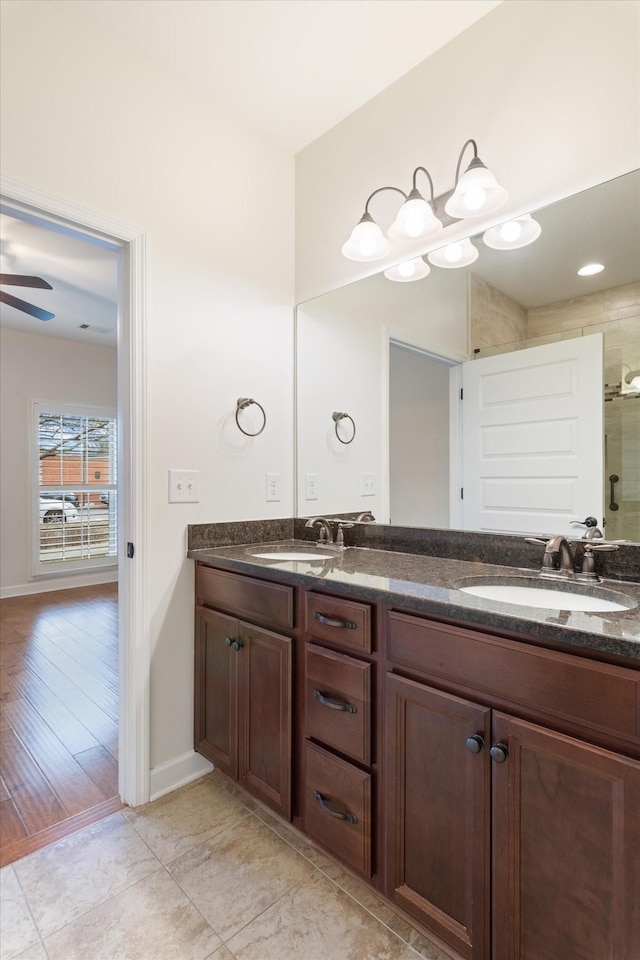 bathroom with ceiling fan, double vanity, a sink, and a shower with door