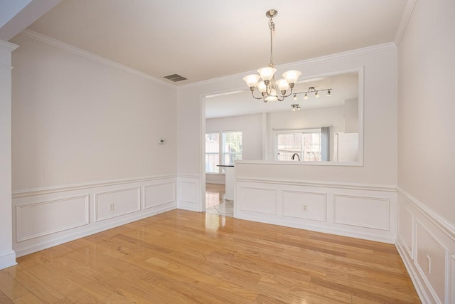 unfurnished dining area with light wood-type flooring, visible vents, a notable chandelier, and ornamental molding