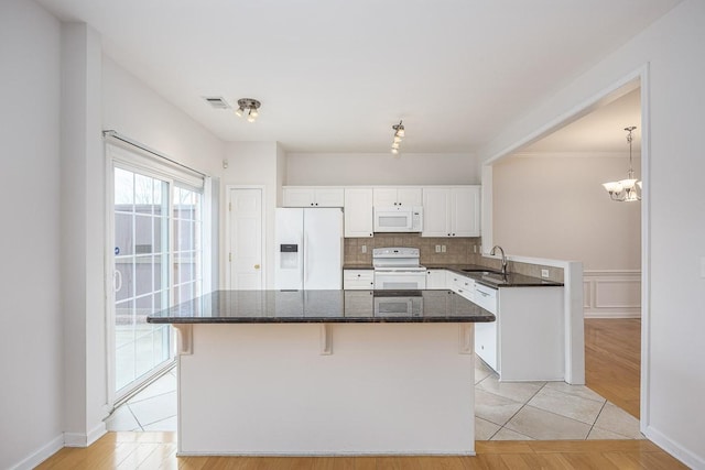 kitchen featuring visible vents, a sink, white appliances, white cabinets, and decorative backsplash