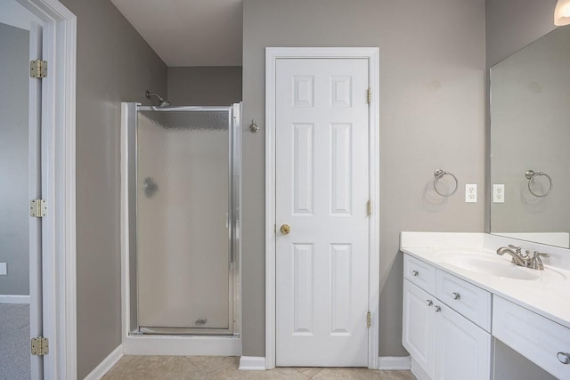 full bathroom with vanity, a shower stall, baseboards, and tile patterned floors