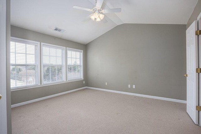 empty room with visible vents, baseboards, light colored carpet, ceiling fan, and vaulted ceiling