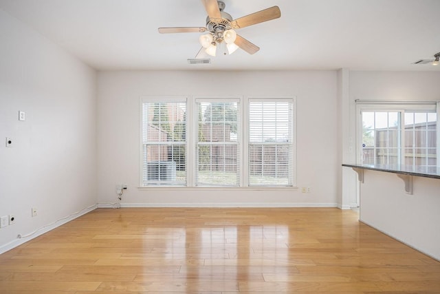 unfurnished living room featuring visible vents, baseboards, light wood-style floors, and a ceiling fan