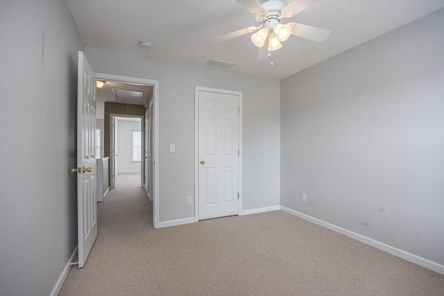 unfurnished bedroom featuring attic access, carpet flooring, a ceiling fan, and baseboards