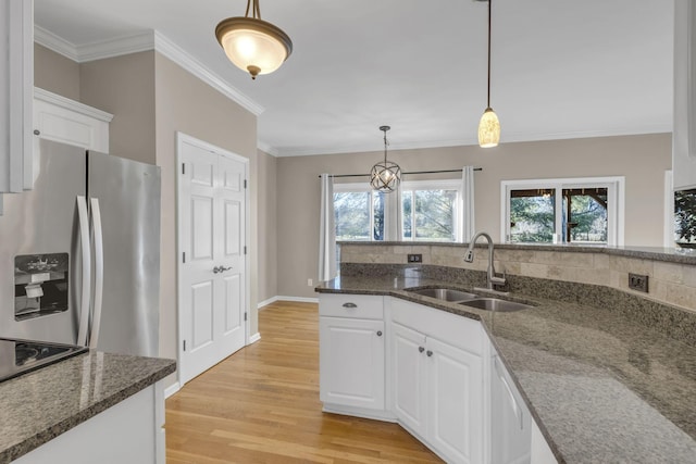 kitchen featuring decorative light fixtures, light wood-style flooring, white cabinetry, a sink, and stainless steel fridge