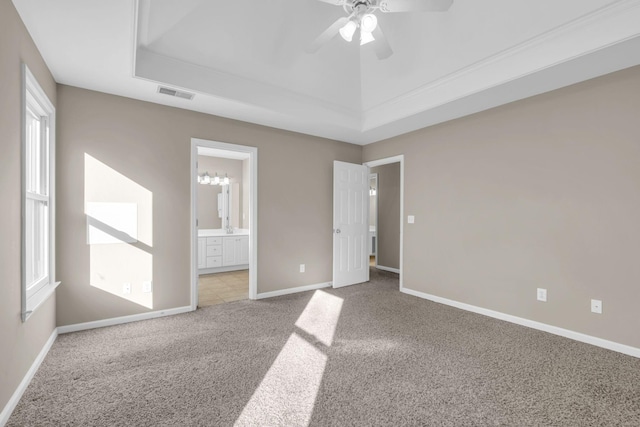 unfurnished bedroom with carpet flooring, a raised ceiling, visible vents, and baseboards