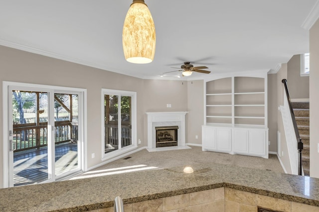 unfurnished living room featuring stairs, carpet floors, a premium fireplace, and a wealth of natural light