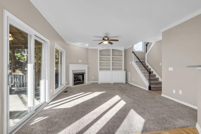 unfurnished living room with ceiling fan, a premium fireplace, baseboards, stairs, and ornamental molding