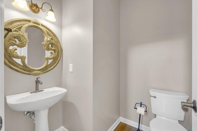 bathroom with baseboards, toilet, and wood finished floors