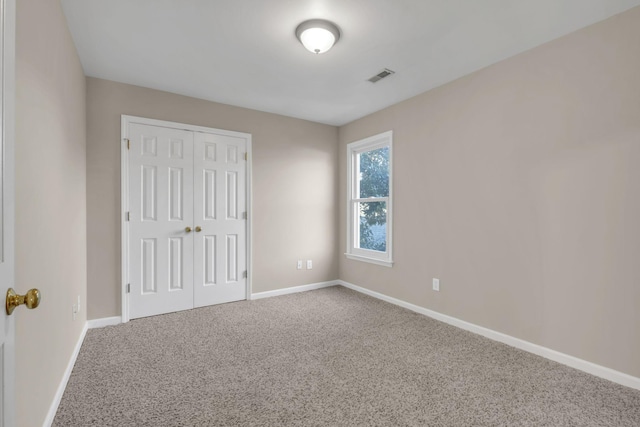 unfurnished bedroom with carpet floors, a closet, visible vents, and baseboards