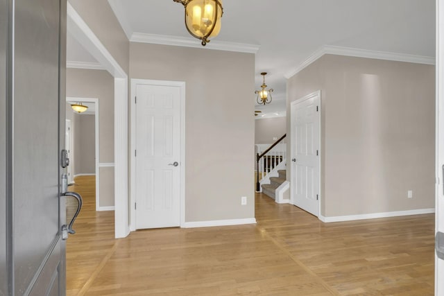 entryway with stairs, ornamental molding, light wood-style flooring, and baseboards