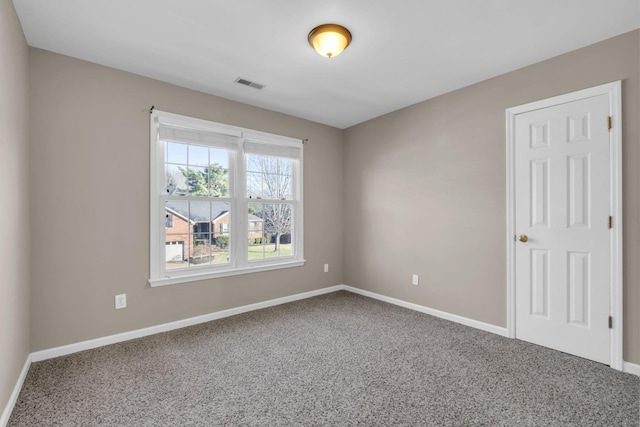 spare room featuring carpet floors, visible vents, and baseboards