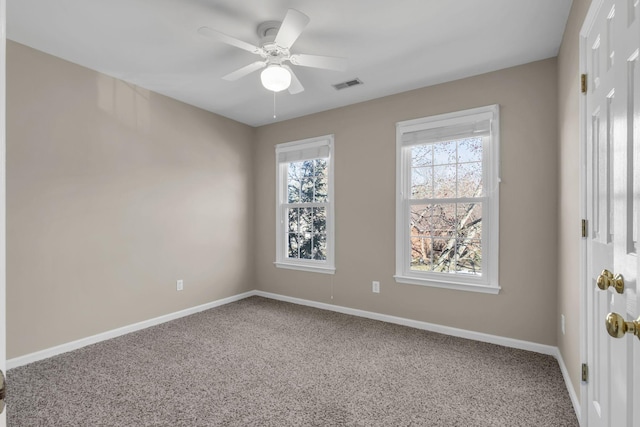 carpeted spare room with a ceiling fan, visible vents, and baseboards