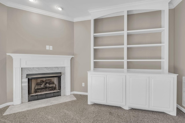 unfurnished living room with built in shelves, carpet floors, a high end fireplace, baseboards, and ornamental molding