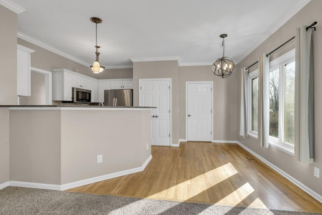 kitchen featuring light wood-style floors, white cabinetry, stainless steel appliances, and ornamental molding