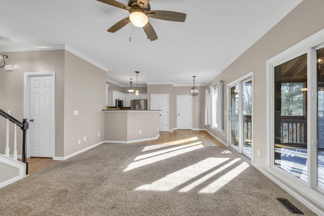 unfurnished living room with baseboards, visible vents, light colored carpet, ornamental molding, and stairs