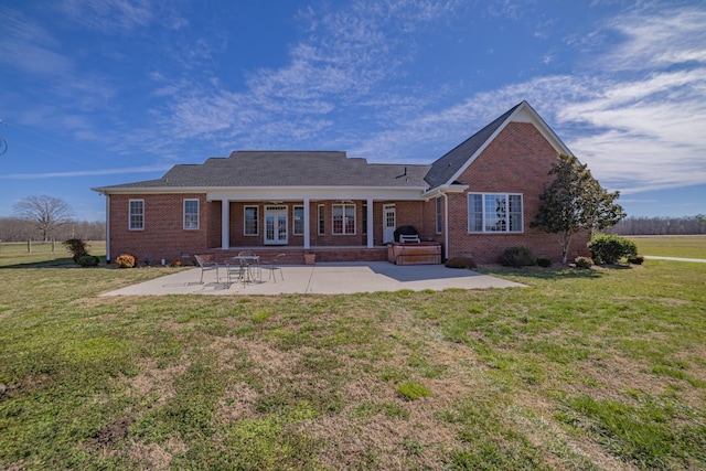 back of house featuring a yard, a patio, brick siding, and french doors