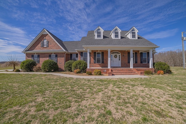 cape cod-style house with brick siding, covered porch, and a front yard