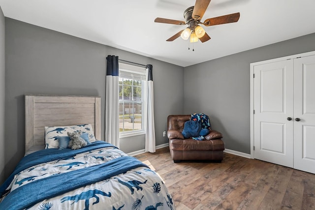 bedroom with a closet, wood finished floors, a ceiling fan, and baseboards