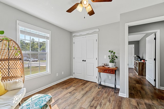 living area with wood finished floors, a ceiling fan, and baseboards