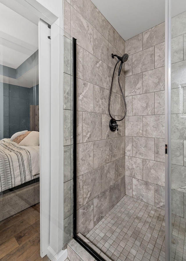 bathroom with ensuite bathroom, a stall shower, and wood finished floors