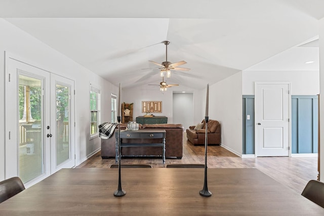 interior space with a ceiling fan, baseboards, vaulted ceiling, and wood finished floors