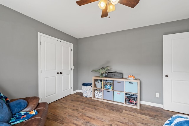 rec room with wood finished floors, a ceiling fan, and baseboards