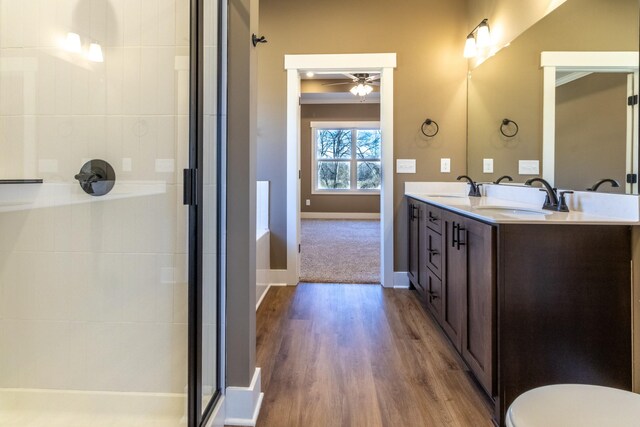 bathroom featuring double vanity, an enclosed shower, a sink, wood finished floors, and baseboards